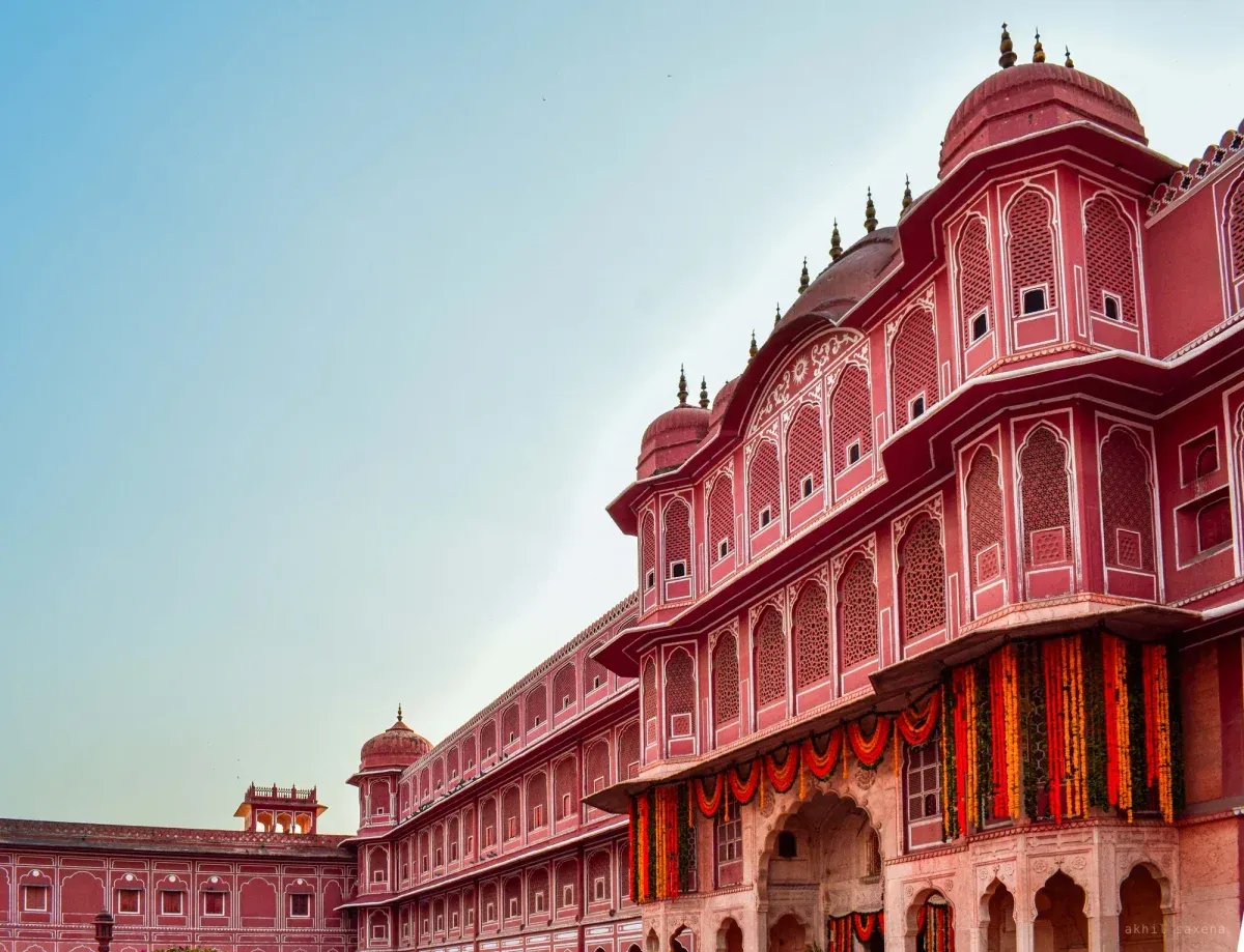 The City Palace's pink sandstone range of domed pavilions and tiered latticed windows, red and marigold garlands hung over the entrance arch.