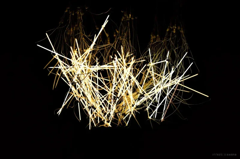 Crossing streaks of white and gold light on black, drawn by moving the camera through a long exposure.